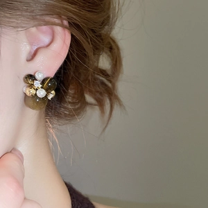 Close-up of zircon and acrylic geometric drop earring worn on a model's ear