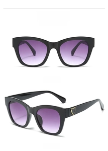 Detailed view of black square sunglasses with purple gradient lenses and gold heart detail.