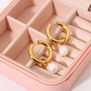Detail of 18k gold plated hoop earrings with drop pearls in a pink jewelry box