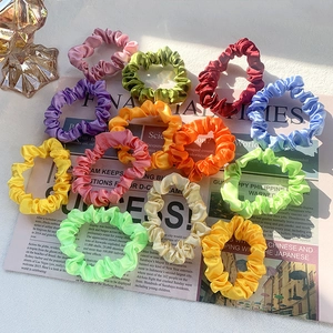 Colorful satin scrunchies set in vibrant pastel tones displayed on a vintage newspaper background