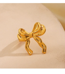 Close-up of 18K gold plated bow ring with mirror polished finish on stone surface