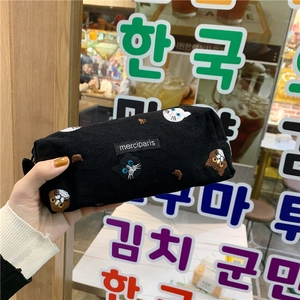 Close-up of black canvas pencil case featuring diverse cat face embroidery and zipper