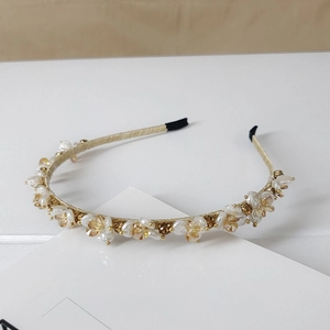 Detail view of crystal and faux pearl cluster on a golden vintage headband base