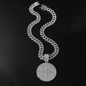 Détail d'une chaîne cubaine argentée glacée avec pendentif médaille croix serti de diamants