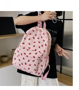 Detailed close-up of a pink corduroy backpack with small strawberry patterns