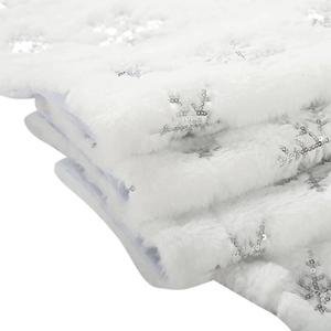 Detailed view of white faux fur Christmas tree skirt with silver sequin snowflakes