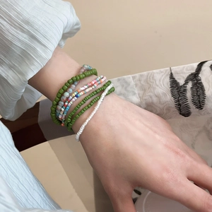 Macro detail of seven bohemian seed bead bracelets stacked on a wrist with colorful layers