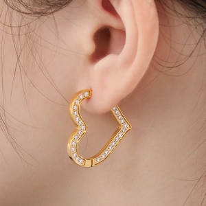 Close-up of heart-shaped gold earring with micro-set cubic zirconia on a female model
