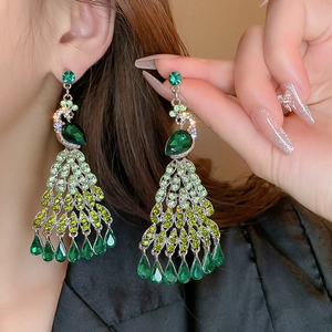Elegant vintage peacock drop earrings with green crystals on a female model