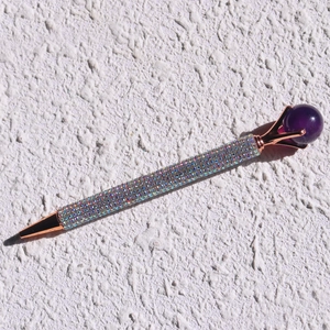 Detailed shot of rose gold metal pen encrusted with colorful crystals and purple top