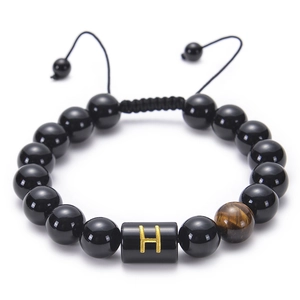Macro detail of obsidian bead bracelet with letter H charm and tiger eye stone