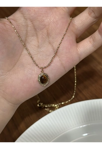 Detail shot of a gold-plated tiger eye stone oval pendant necklace with elegant bead chain