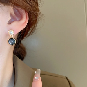 Close-up of model wearing oval faux tiger eye and gold plated silver stud earrings