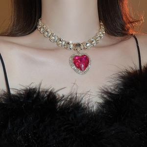 Close-up of luxury gold heart necklace featuring a large pink gemstone and clear crystals