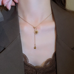 Gros plan d'un pendentif tournesol doré avec œil de tigre et pompon sur le cou