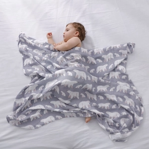 Breathable muslin baby blanket with polar bear pattern shown in a soft nursery setting