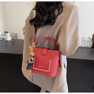 Detail of red bucket bag with wide ethnic strap, gold studs and bunny charm