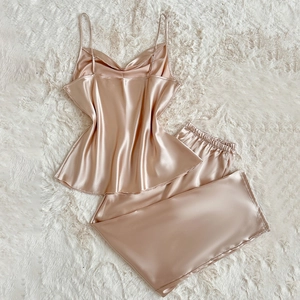 Elegant champagne satin pajama set with camisole top and trousers on plush rug