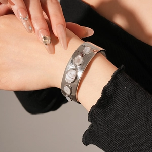 Détail du bracelet ouvert doré avec incrustations de résine effet marbre blanc