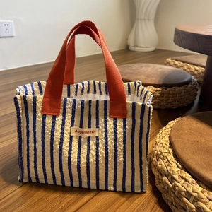 Dettaglio della borsa tote a righe blu con trama plissettata e manici in fettuccia arancione