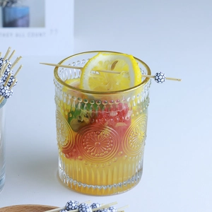 Vintage embossed glass cup with gold rim featuring lemon slices and fresh yellow drink