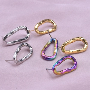 Detailed macro view of irregular wavy oval stud earrings in silver, gold and rainbow finish