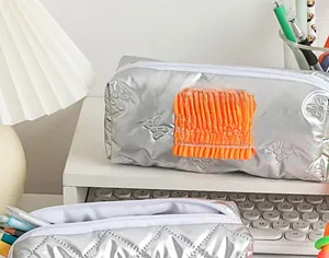 Detail view of silver large capacity pencil case with bow embossing and orange lace detail