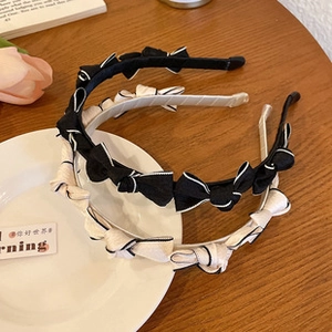 Detail view of black and cream fabric headbands with delicate bow ties on a ceramic plate