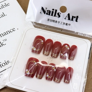 Handmade red press-on nails with elegant pearls and gold wire details in packaging