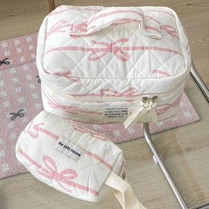 Close-up of quilted cosmetic bags with pink bow pattern on a modern wooden floor