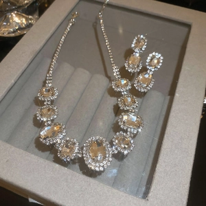 Detailed view of silver oval crystal choker necklace and earrings on gray velvet