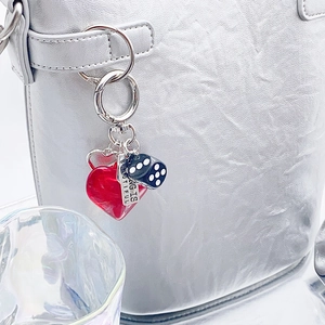 Macro view of silver keychain with red heart, black dice, and engraved metal tag