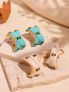 Detail of blue and beige C-shaped leopard print earrings on decorative stone