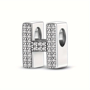 Close-up of silver-plated bead charm with letter H shape and pavé-set rhinestones