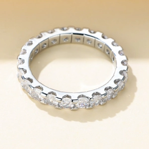 Close-up of a silver ring with a full circle of sparkling zircons on a beige base
