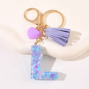 Detailed close-up of purple heart tassel keychain with resin letter L and gold clasp