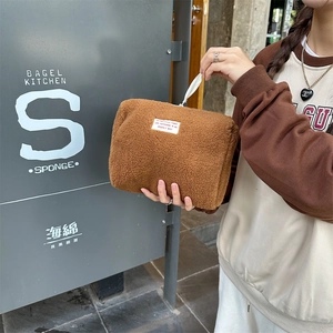Close-up of soft brown faux shearling makeup bag with a minimalist woven label
