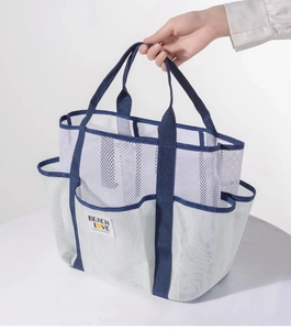 Detail of white mesh beach bag with blue straps and pocket compartments for storage