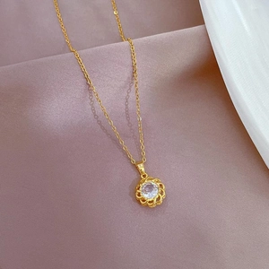 Macro view of gold flower pendant with sparkling zircon on soft lavender fabric
