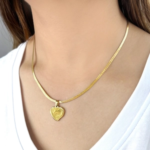 Minimalist gold stainless steel necklace with textured heart and Z pendant on model