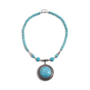 Ethnic turquoise beaded necklace with a round vintage silver pendant on white background