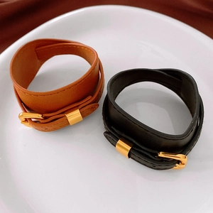 Detail of vintage faux leather chokers in black and brown with gold metal buckles