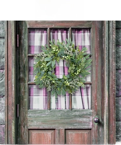 Close-up of artificial eucalyptus wreath with white berries on a vintage wooden door