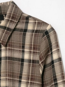 Detailed close-up of checkered shirt collar and shoulder seams in brown woven fabric