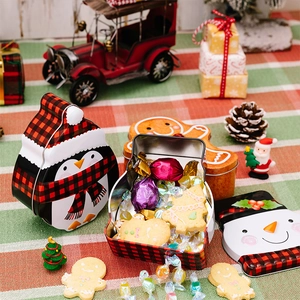 Close-up of penguin and gingerbread man Christmas tin boxes filled with cookies and candies