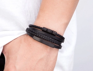 Close-up of men's layered black leather bracelet with braided cord and metal accents