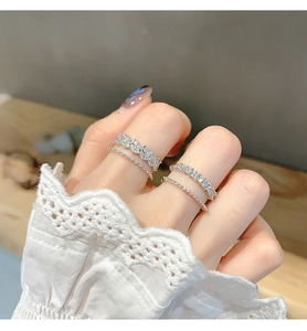 Set of four minimalist silver rings with sparkling zircon accents on a hand