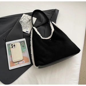 Detail shot of a black tote bag with white plush trim on a blazer with lifestyle props