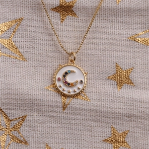 Detailed close-up of golden necklace pendant with enamel crescent moon and colorful stars