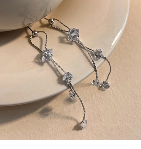 Detail of silver long tassel earrings with sparkling cubic zirconia on ceramic tray